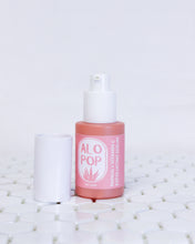 Load image into Gallery viewer, Papaya + Vitamin C Exfoliating Serum in a glass coral colored bottle with a white cap off sitting next to the bottle, the pump top of the bottle is also white. The label of this glowing facial serum is pinky salmon colored with white text. The text has the ALOPOP logo and the product title. The serum bottle is sitting on geometric white tiles with a white background behind it. 
