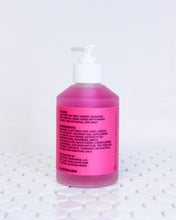 Load image into Gallery viewer, Glass bottle of Rose Hip and Green Tea Gel facial cleanser. Gel is hot pink with a white pump top lid and a hot pink label with black text on it. The bottle is facing backwards so you can see the black text with the product usage instructions, natural ingredients list and ALOPOP address and website. The gentle face wash bottle is sitting on geometric white tiles with the white background behind it.