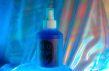 Load image into Gallery viewer, Chamomile + Tea Tree Toning Mist in a glass mist bottle. Liquid is purple and the label has the ALOPOP logo and title of this gentle face toning mist in black. The bottle is sitting on a glass dish with a dreamy rainbow haze behind it.